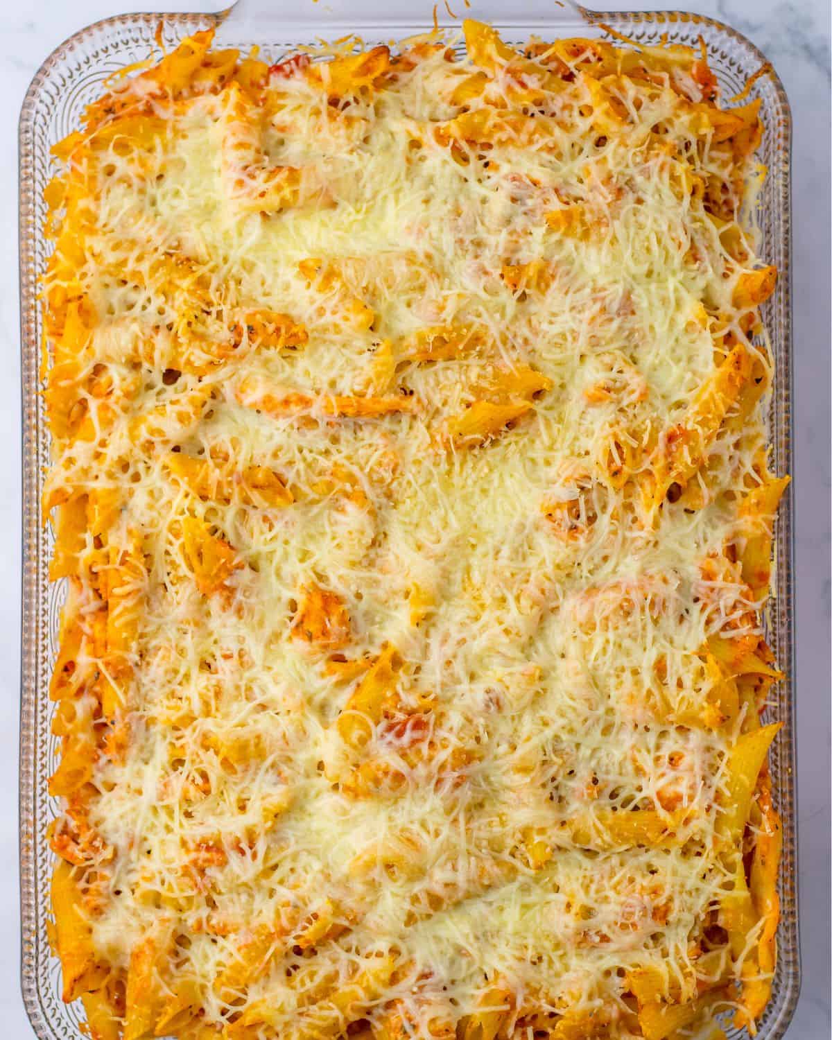 A large baking dish with pasta, chicken, and marinara sauce topped with mozzarella cheese.