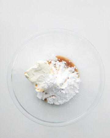 Cream cheese, confectioners sugar, and vanilla extract in a glass bowl for cream cheese filling.