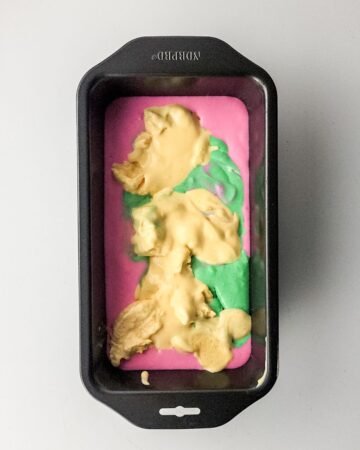 A loaf pan with rainbow sherbet in the pan.