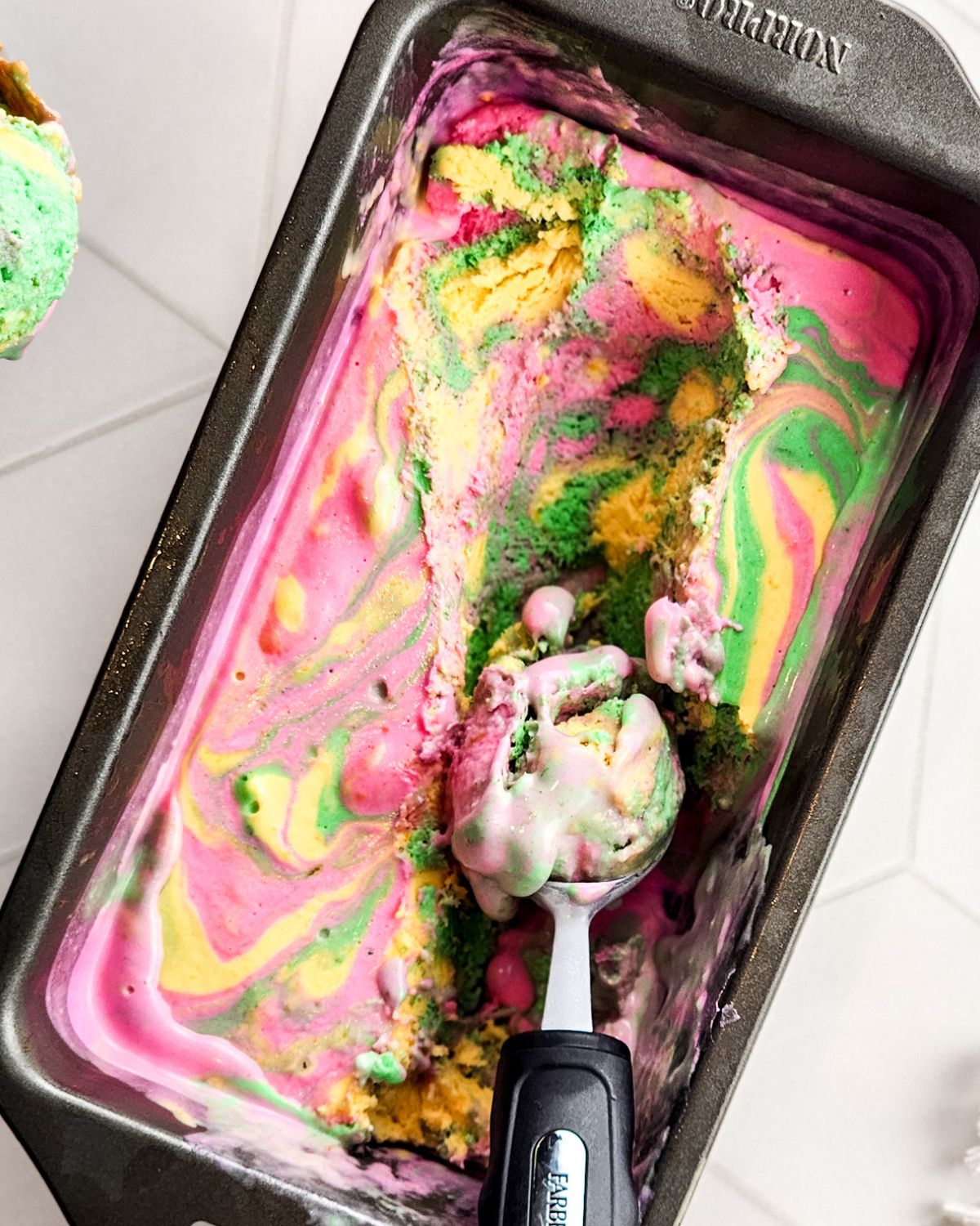 A loaf pan with rainbow sherbet in the loaf pan.