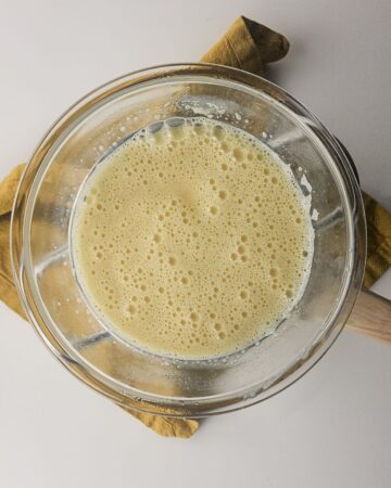 A glass bowl with whipped sweetened condensed milk and eggs with a bubbly topping.