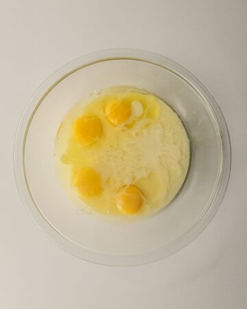 Eggs and sweetened condensed milk in a glass bowl to make salted caramel ice cream.