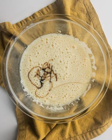 A glass bowl with whipped eggs and sweetened condensed milk with salted caramel.