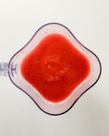 A blender with blended strawberries to make sorbet.