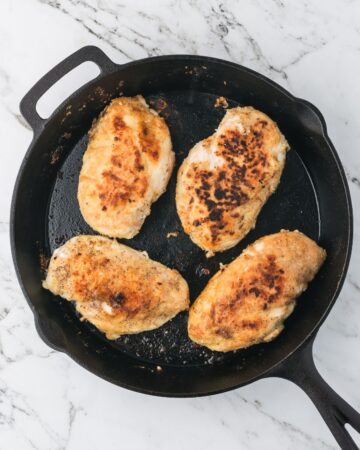 Chicken breasts seasoned with salt, black pepper, and all purpose flour sauteed in a cast iron pan.