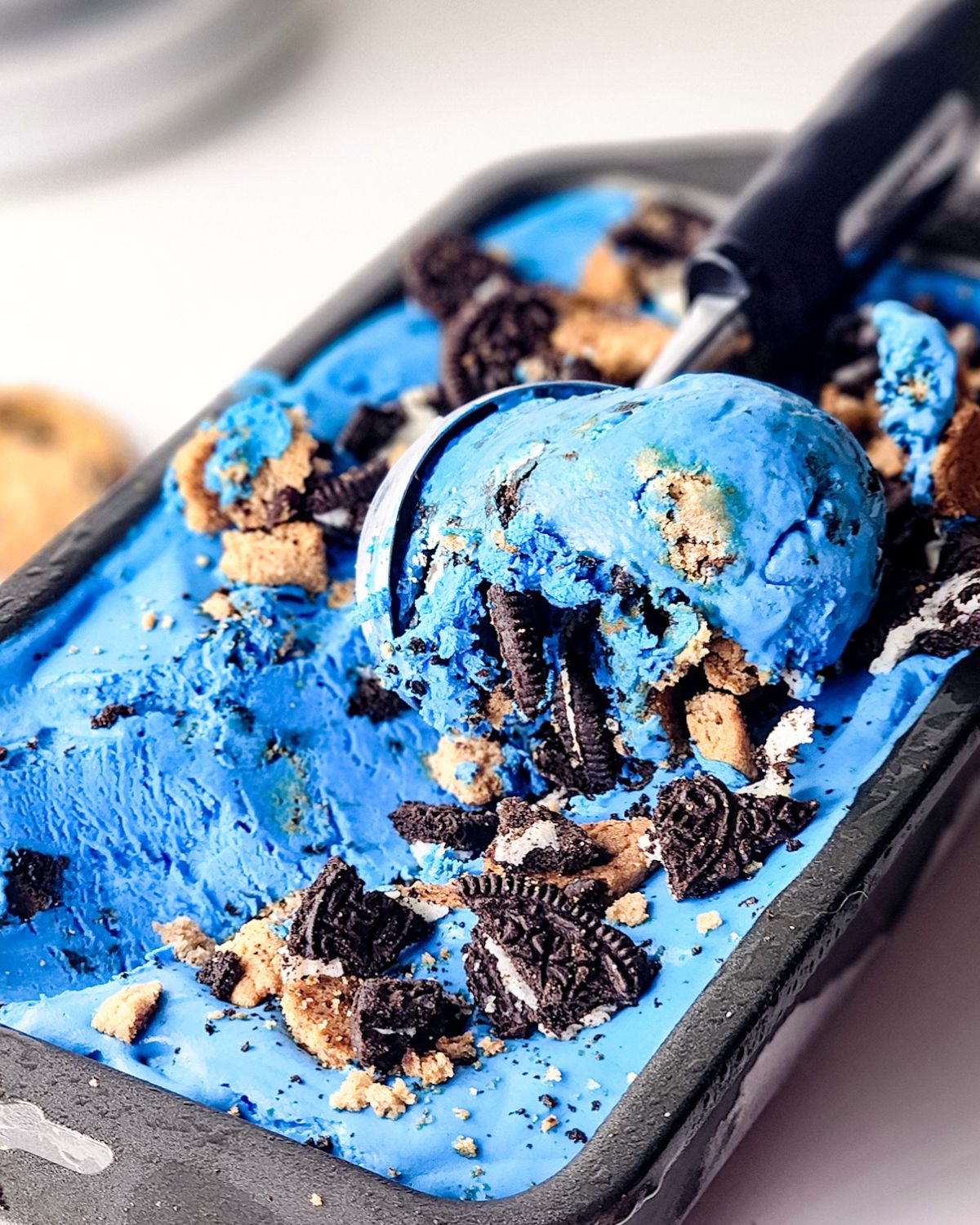 Blue cookie monster ice cream being scooped out of a loaf pan.