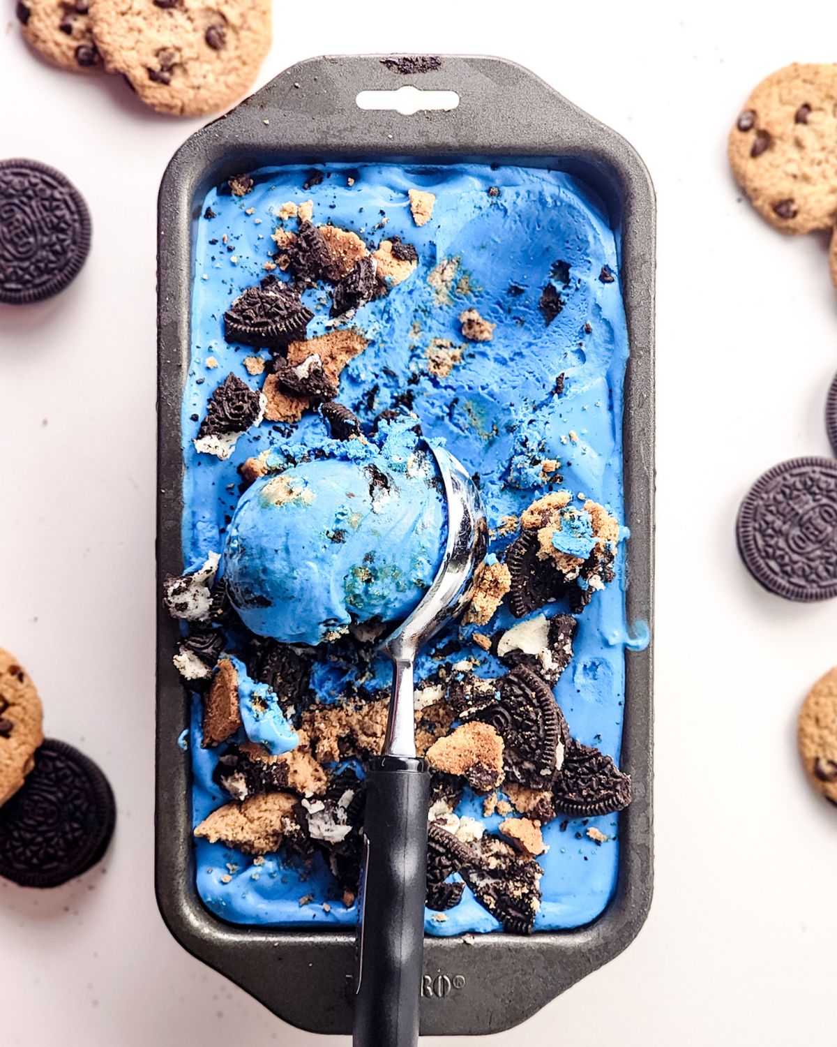 A loaf pan with blue cookie monster no churn ice cream being scooped out of the pan.