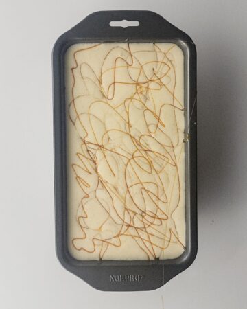 A loaf pan with salted caramel ice cream topped with a swirl of caramel sauce. 