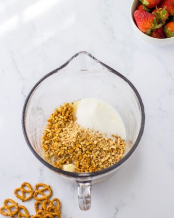A glass bowl with crushed pretzels and sugar to make a pretzel pie crust. 