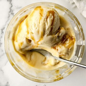 A glass bowl of salted caramel ice cream with swirls of caramel.