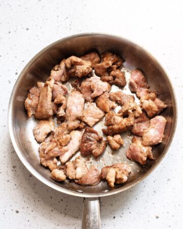 A saute pan with cooked pork for pork chop suey.