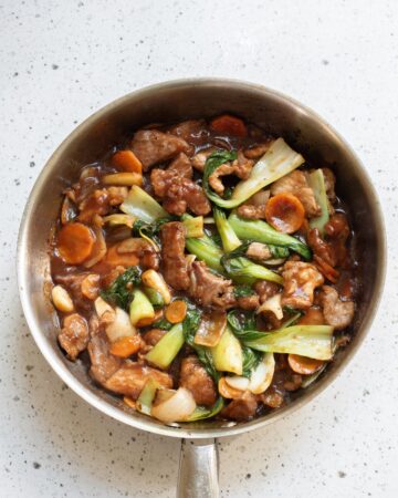 A saute pan with pork and vegetables for a pork chop suey dinner. 