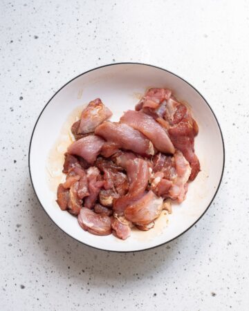 A white bowl with marinated pork for pork chop suey recipe.