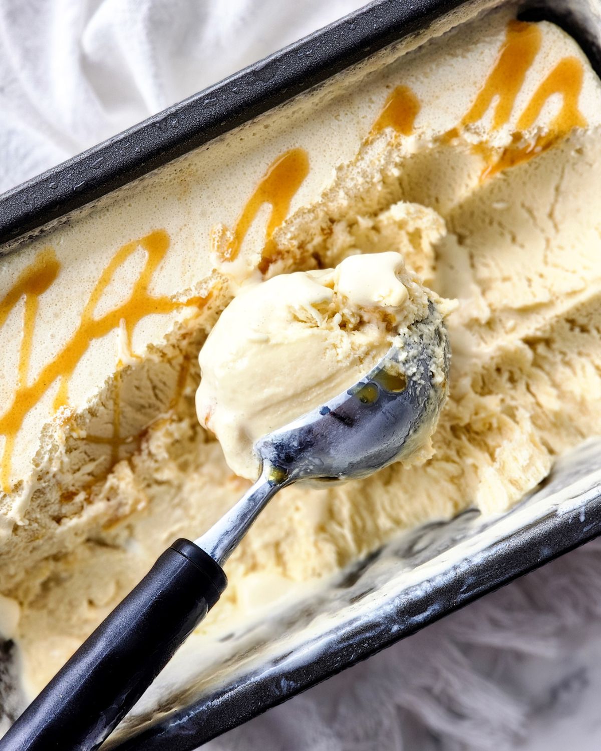 Salted Caramel Ice Cream in a loaf pan being scooped out of the tub.