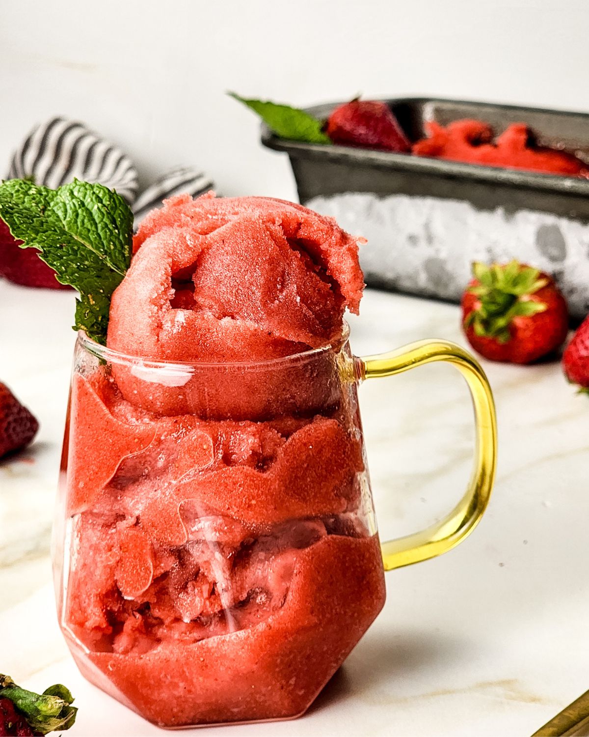 Strawberry sorbet in a glass with fresh mint.