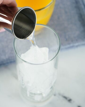 Tequila being pouring into a glass to make a tequila sunrise.