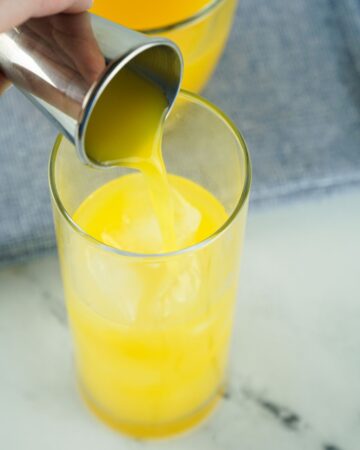 A glass with tequila and orange juice to make tequila sunrise cocktail.