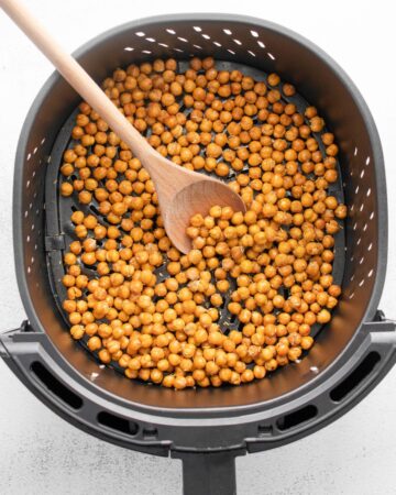 Chickpeas in an air fryer vessel with a rosemary garlic seasoning.
