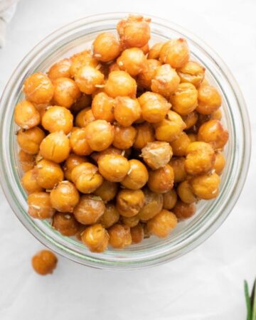 A glass bowl with air fried chickpeas with a garlic and rosemary seasoning. 