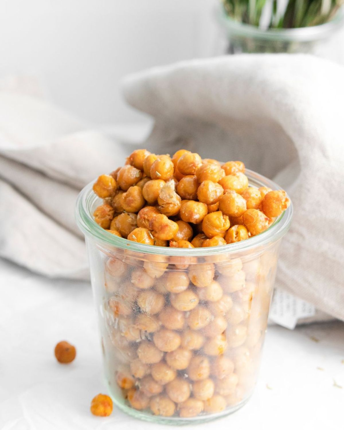 A glass jar filled with chickpeas with rosemary garlic seasoning made in the air fryer.
