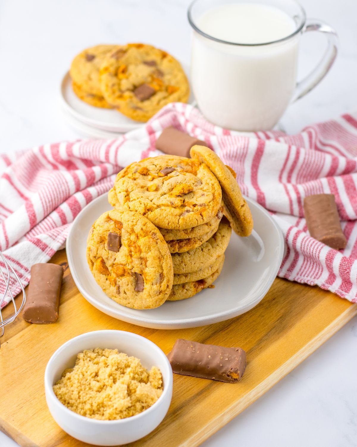 Homemade Butterfinger cookies on a plate with candy on the side.