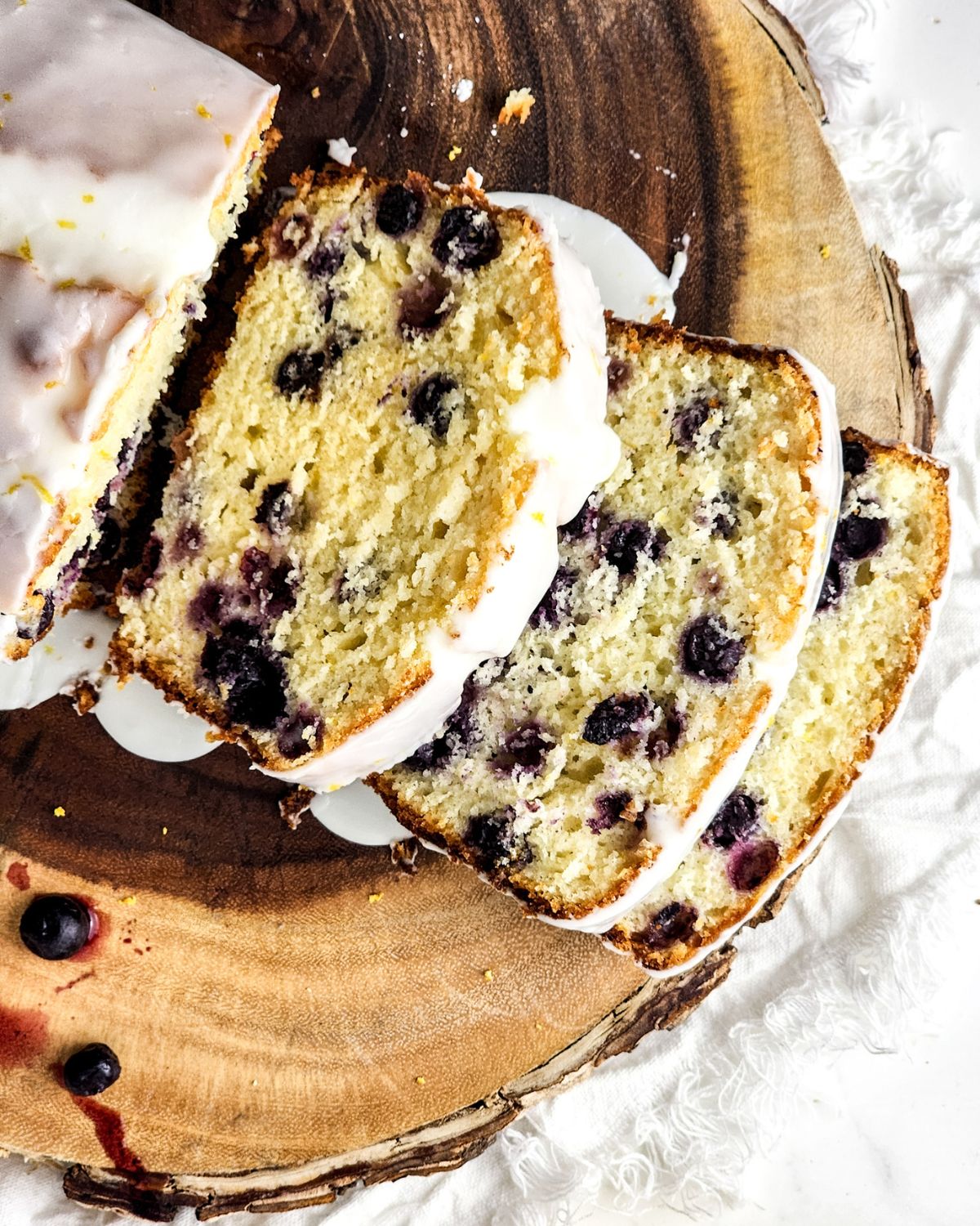 Sliced glazed blueberry lemon loaf on a platter.