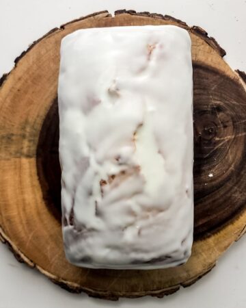 A glazed blueberry lemon loaf on a wooden platter.