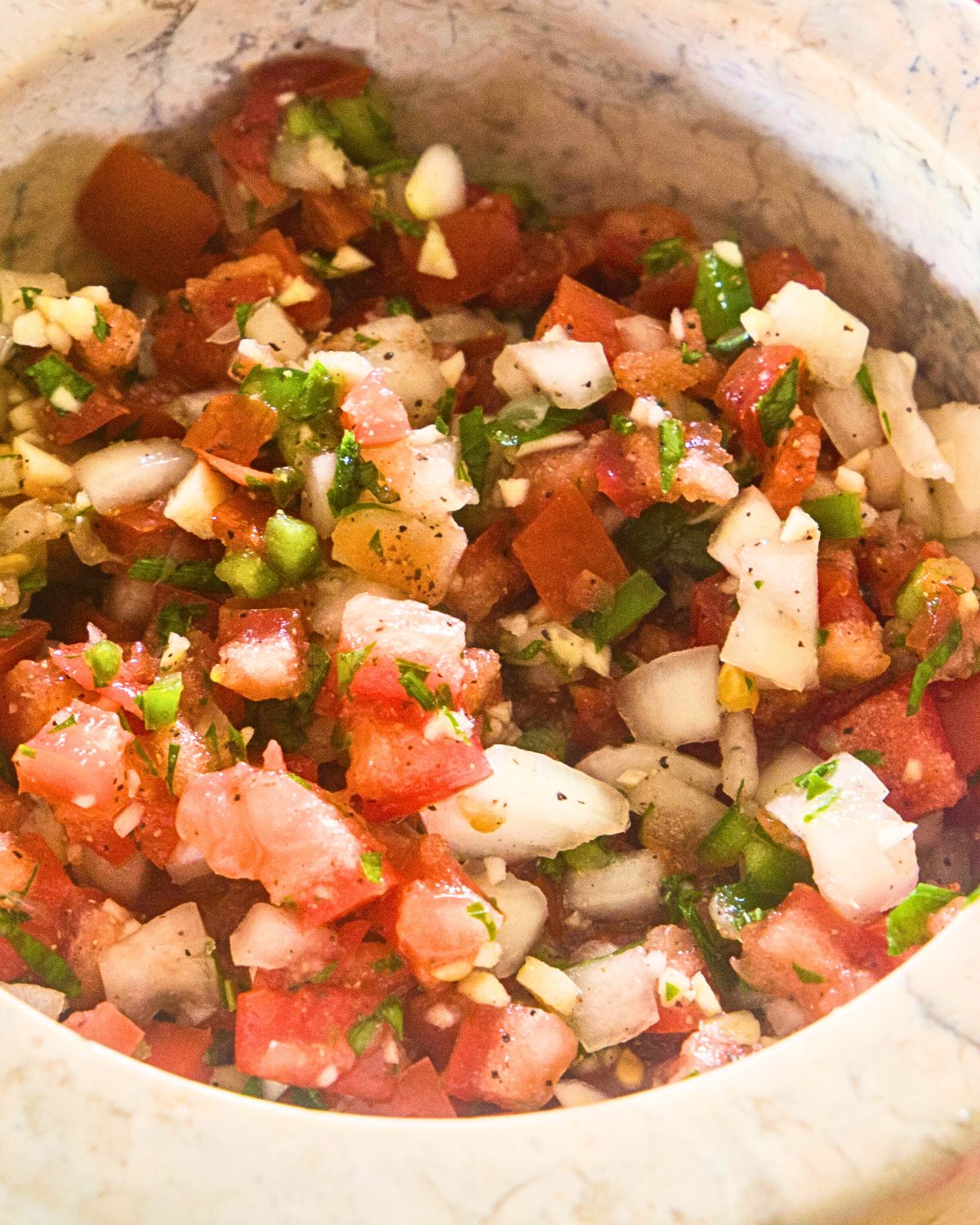 A bowl with fresh tomatoes, jalapeno, and onion for authentic pico de gallo.