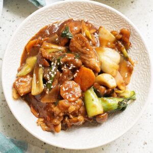 A white bowl with sauteed pork and vegetables to make pork chop suey.