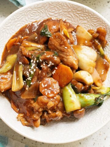 A white bowl with sauteed pork and vegetables to make pork chop suey.