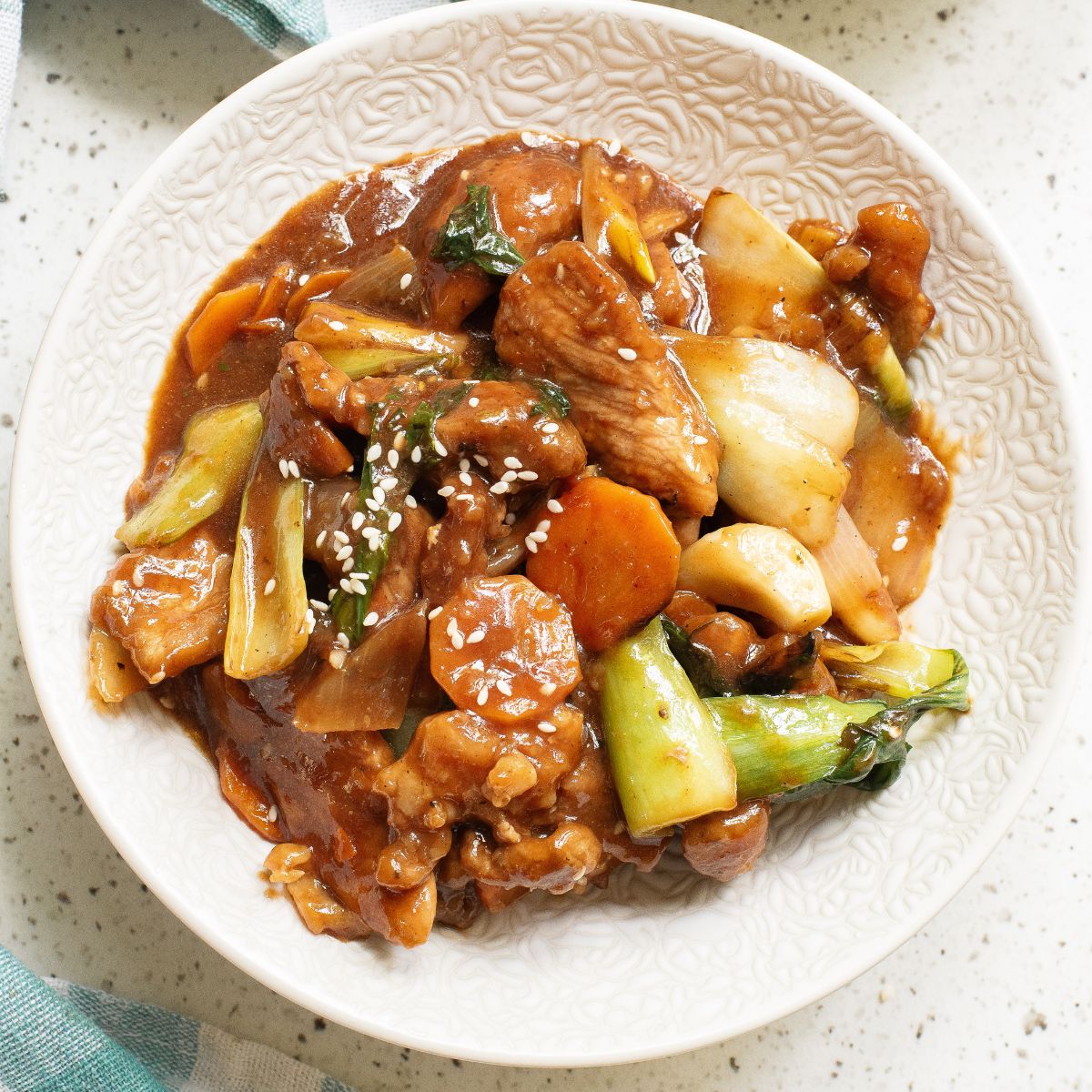A white bowl with sauteed pork and vegetables to make pork chop suey.