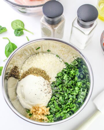 A large silber bowl with ingredients to make ricotta spinach stuffing for chicken.