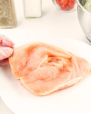 A boneless chicken breast sliced open to be stuffed with a ricotta spinach filling.