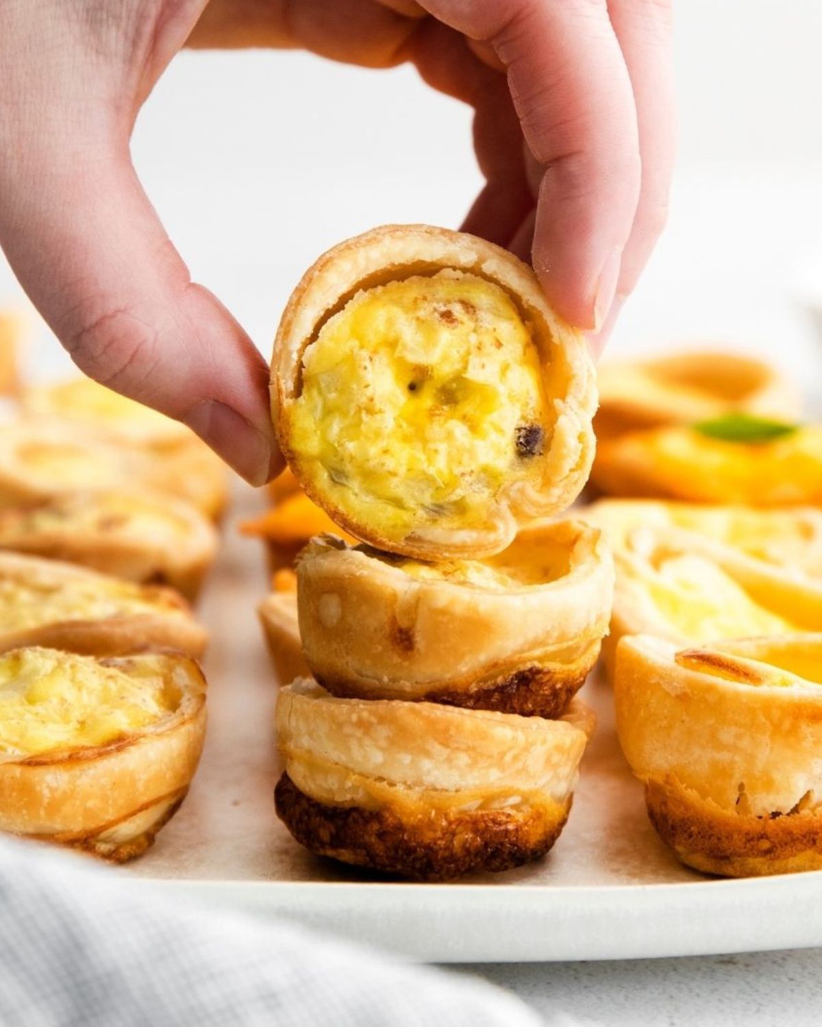 Small quiche in pie crust being held by a hand.
