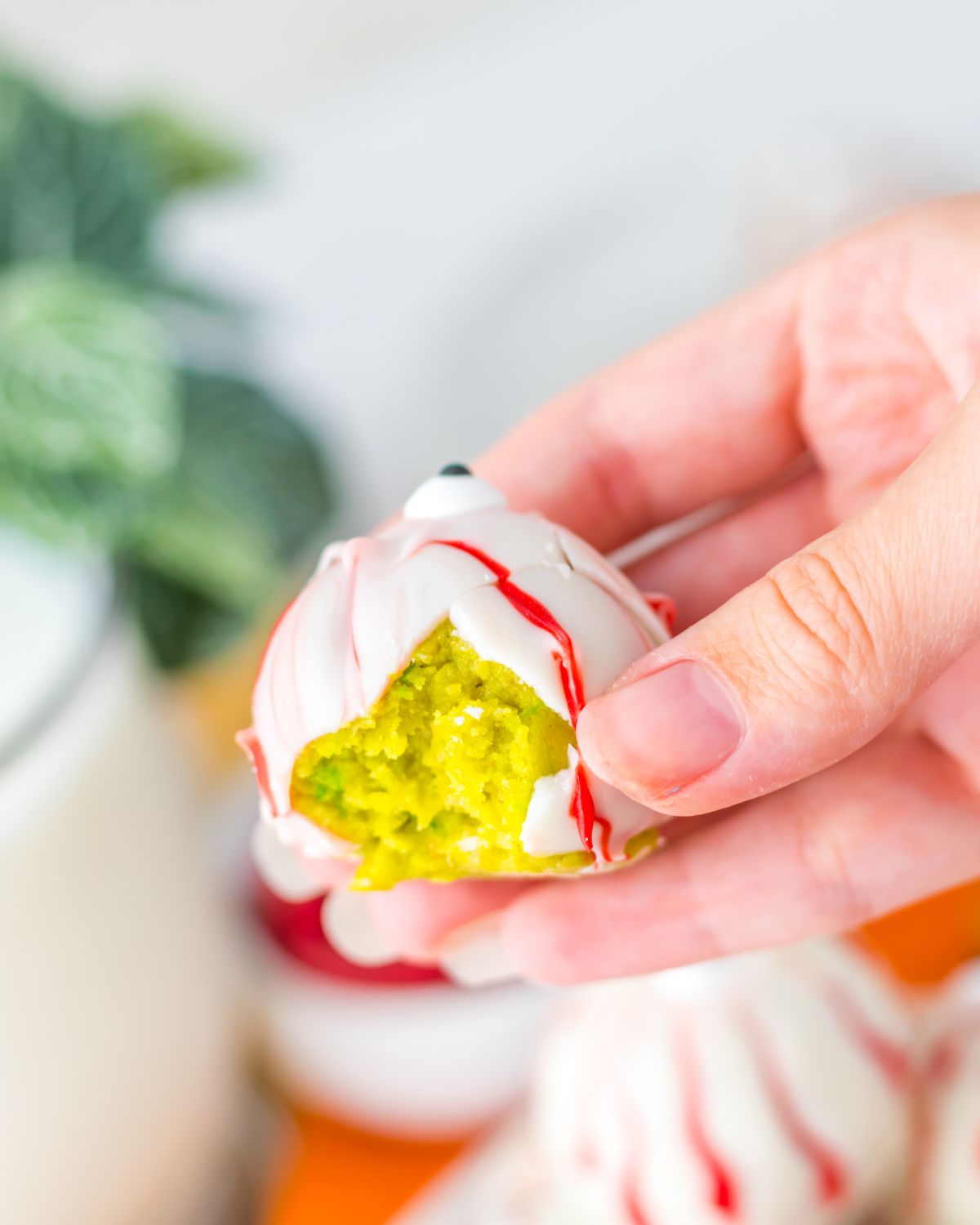 A halloween truffle with a green filling and a white almond bark and a bite out of the trufffle. 