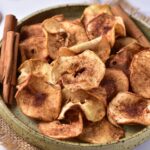 Baked apple chips with cinnamon in a bowl.