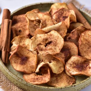 Baked apple chips with cinnamon in a bowl.