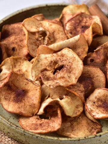 Baked apple chips with cinnamon in a bowl.