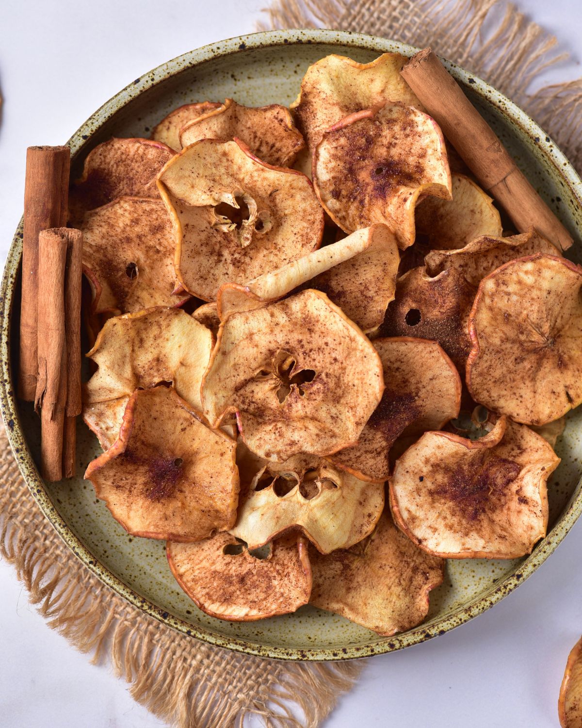 A bowl of crispy baked apple chips with a cinnamon coating.