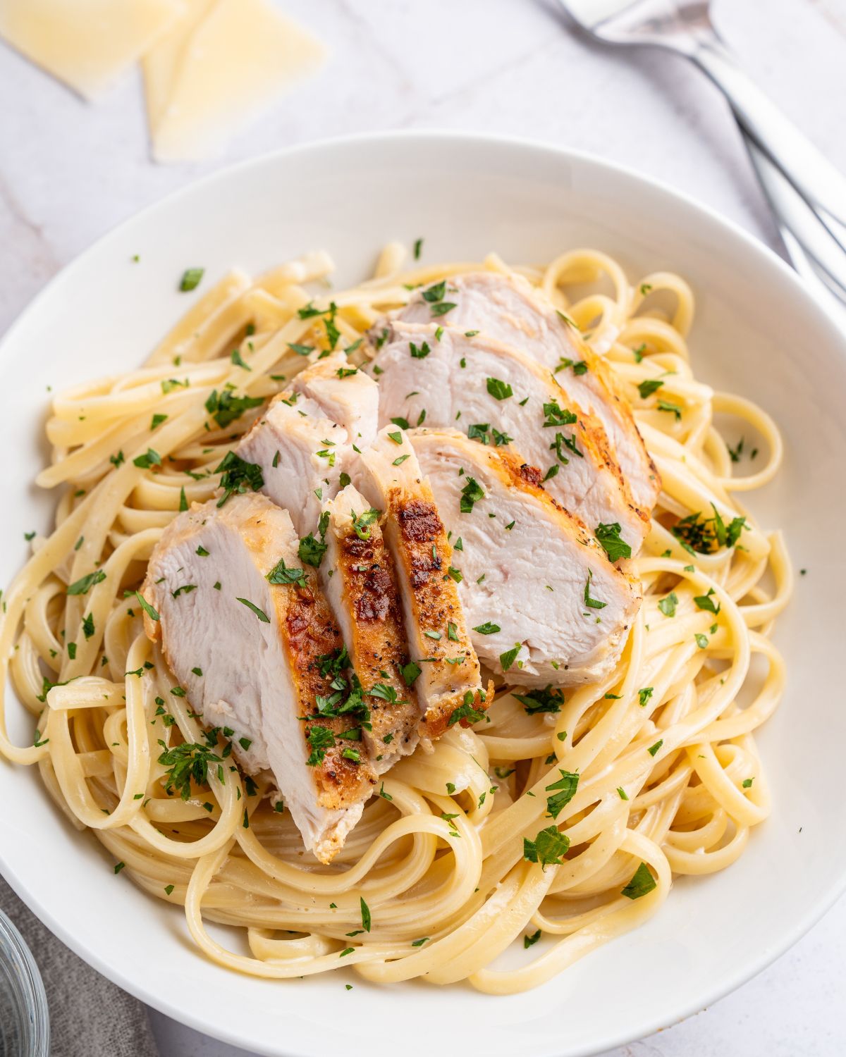Linguine in an alfredo sauce with chicken in a bowl.