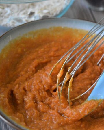 A bowl of pumpkin puree and milk being combined for a cranberry pumpkin oat bar.