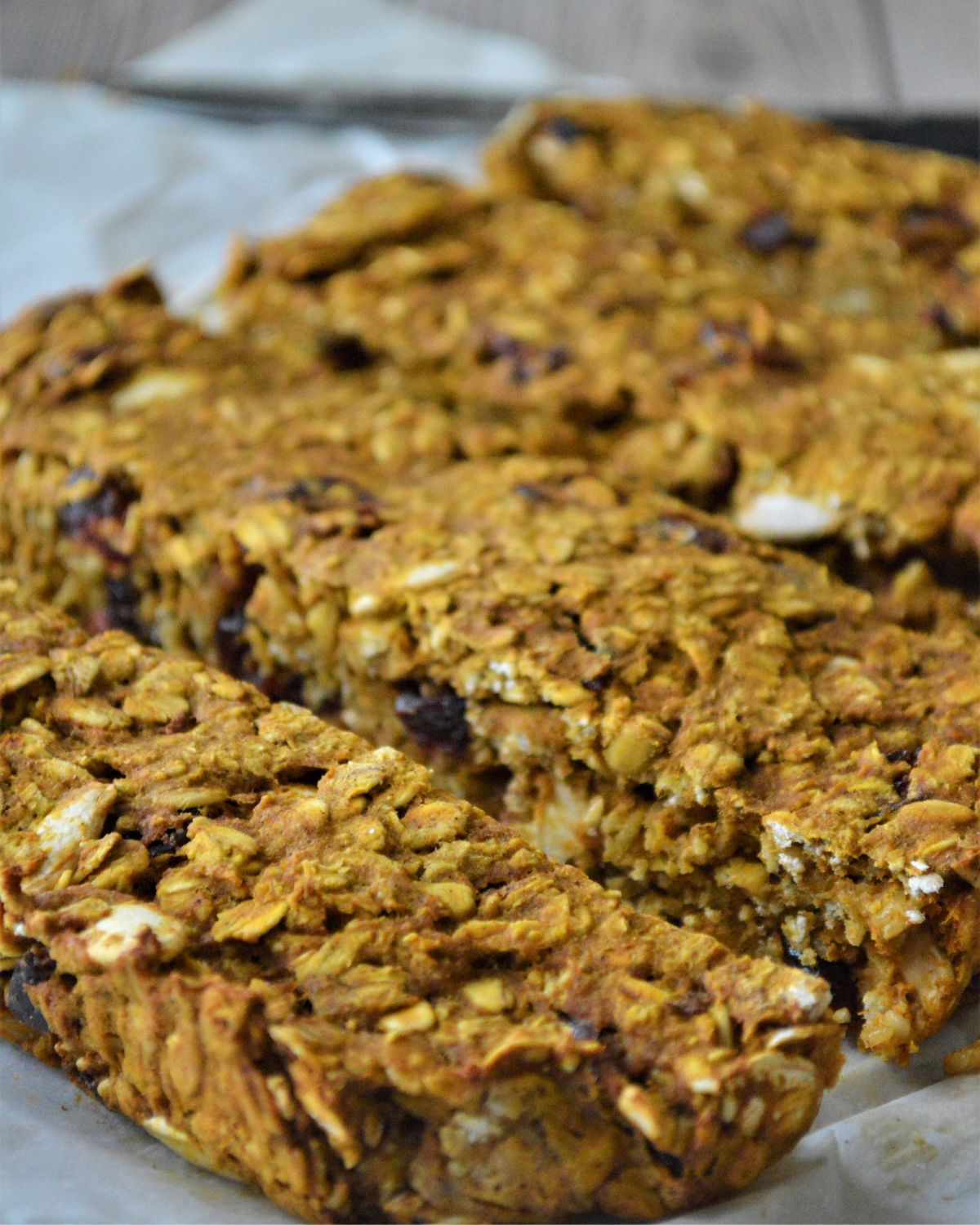 Sliced pumpkin oat bars with cranberries on a baking sheet.