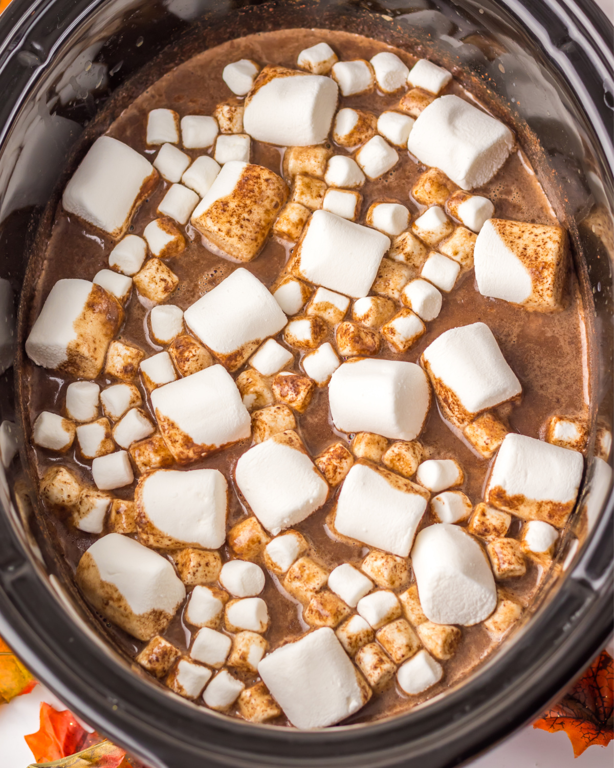 A slow cooker vessel with pumpkin puree, milk, pumpkin spice to make pumpkin spice hot chocolate. 