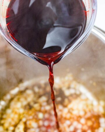 Wine being poured into an Instant Pot vessel for Instant pot beef Bourguignon.