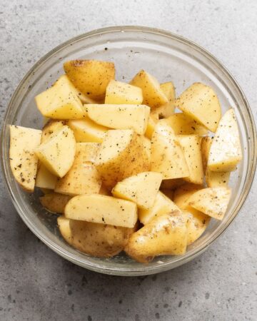 A glass bowl with sliced potato wedges.