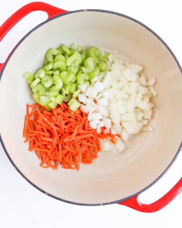 A Dutch oven with onions, celery, and carrots for the base of chicken gnocchi soup.