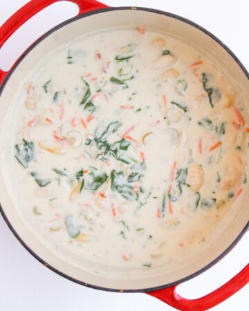 A Dutch oven with creamy soup filled with chicken gnocchi soup. 