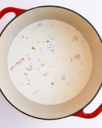 A Dutch oven with heavy cream added to vegetables for the base of chicken gnocchi soup.