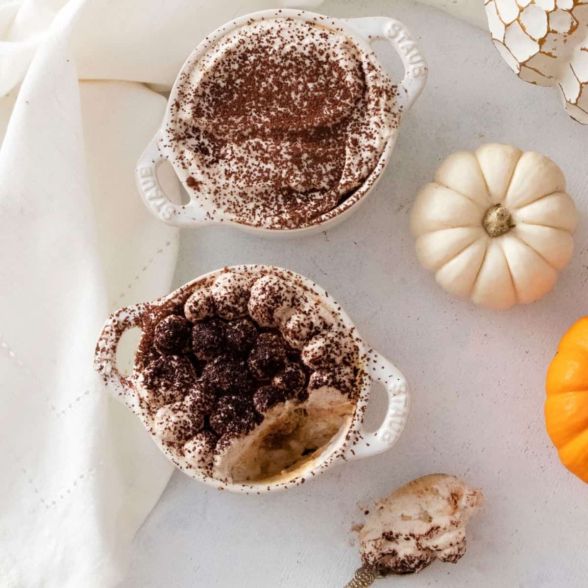 Pumpkin tiramisu in small cocottes with pumpkin mascarpone. The tiramisu is topped with cocoa powder.