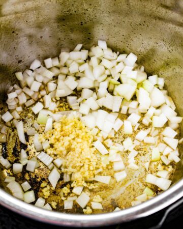 Instant pot with diced onions being sauteed. 